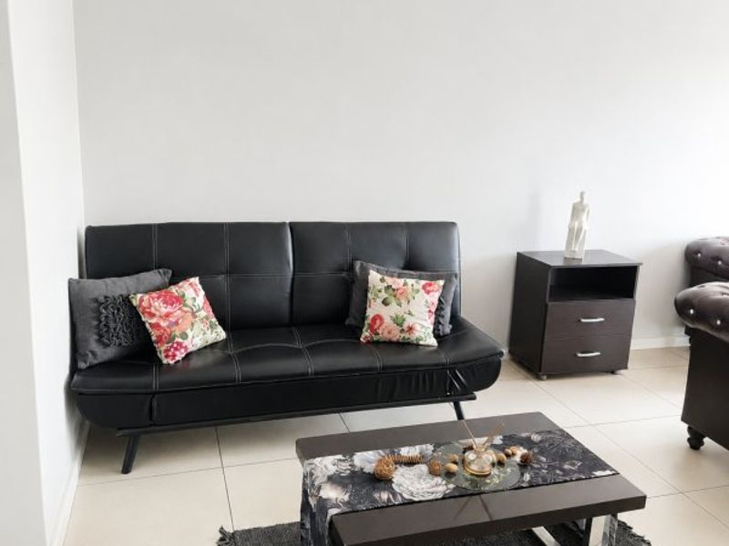 A bright living room area featuring neutral tiled flooring and a clean, minimalist aesthetic with coved ceiling detailing.