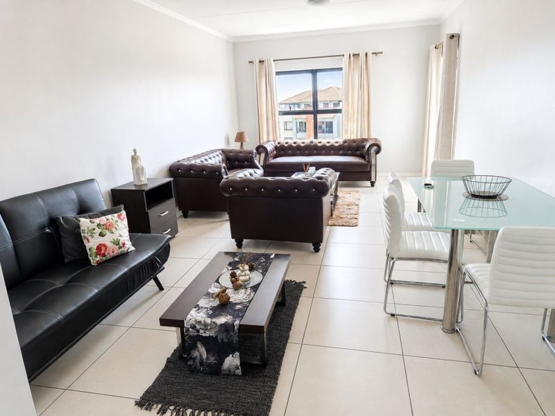 Spacious open-plan living and dining area featuring neutral tiled flooring and large windows, providing a bright and versatile layout for modern apartment living.