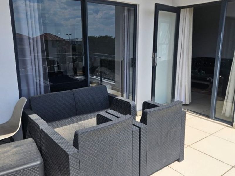 A covered balcony featuring tiled flooring and large sliding glass doors providing access to the interior living space.