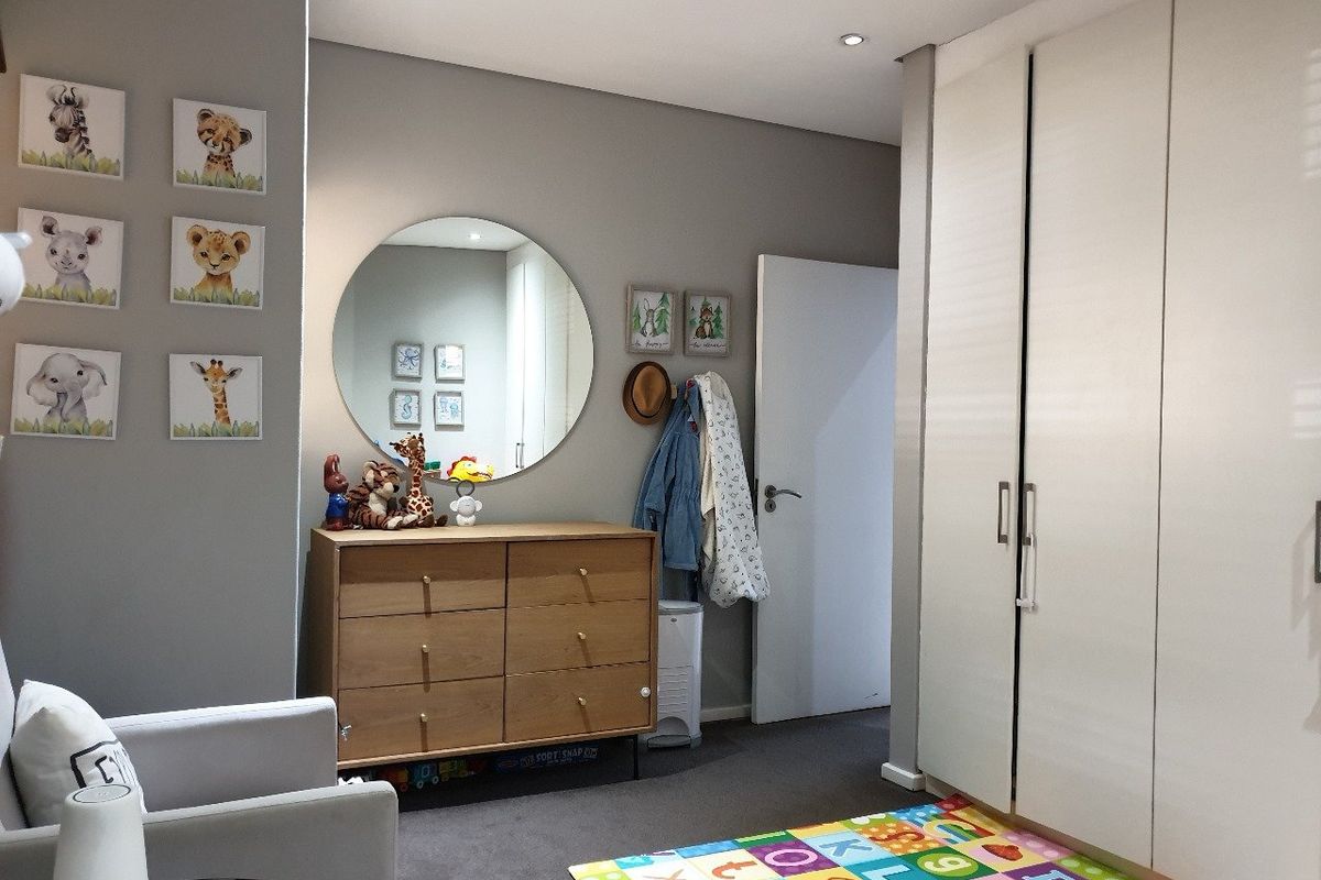 A well-maintained bedroom featuring neutral grey walls, fitted floor-to-ceiling cupboards, and recessed downlighting.