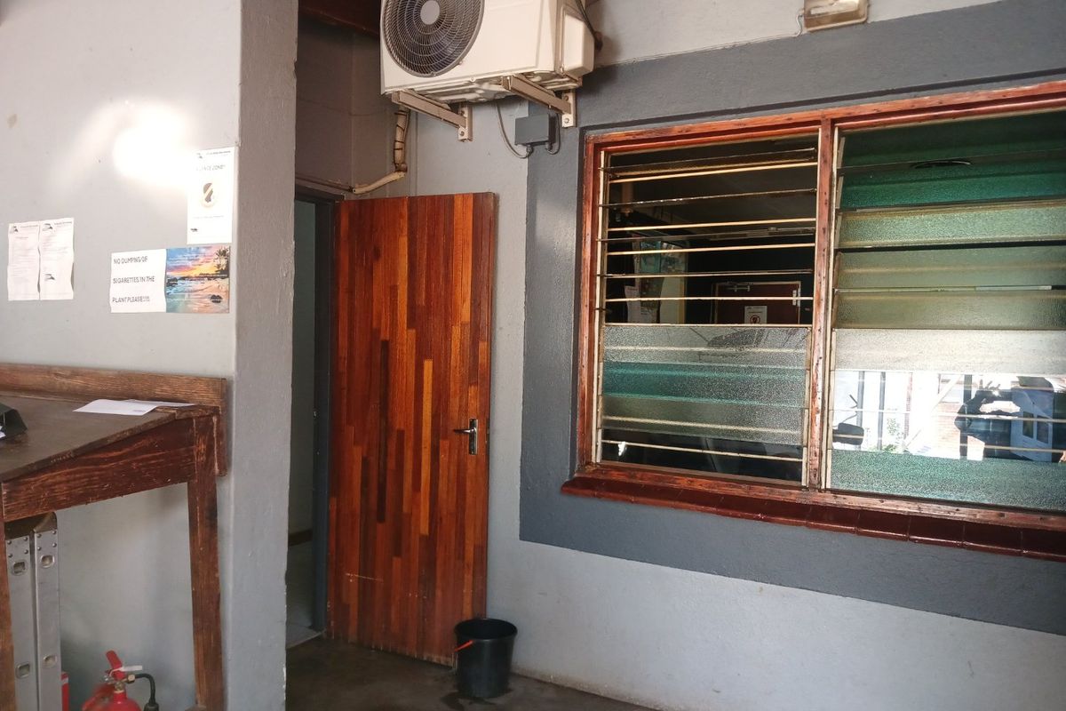 A covered exterior utility area featuring a wooden door, louvre windows, and a wall-mounted air conditioning unit.