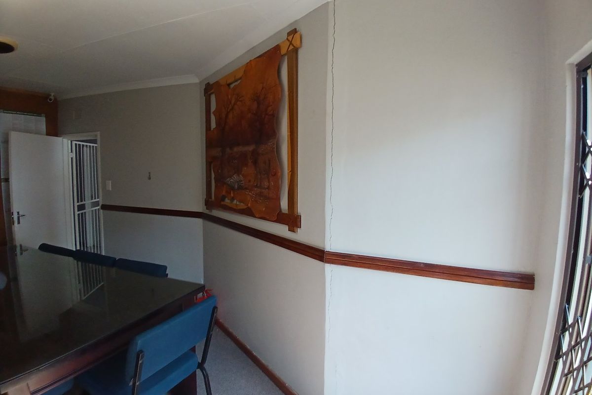 A living area featuring a wooden dado rail and security fixtures, showing a visible vertical crack on the wall requiring maintenance.