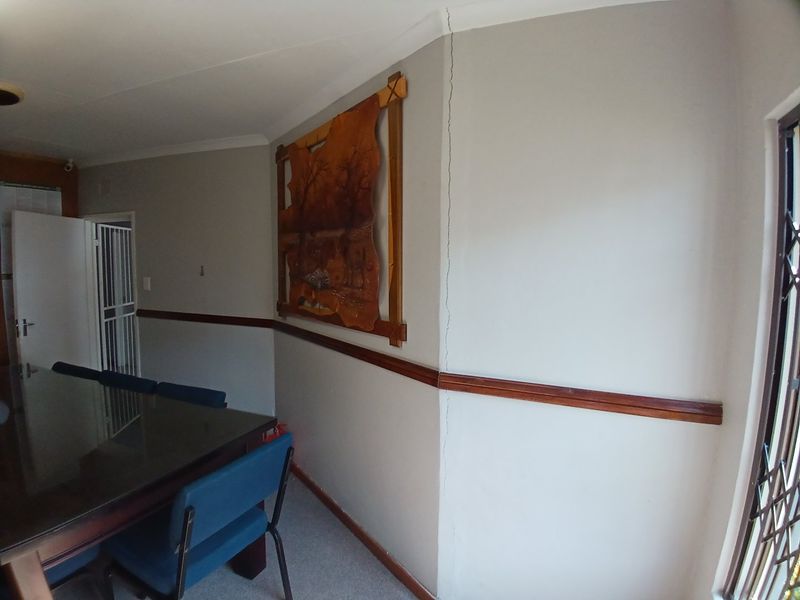 A living area featuring a wooden dado rail and security fixtures, showing a visible vertical crack on the wall requiring maintenance.