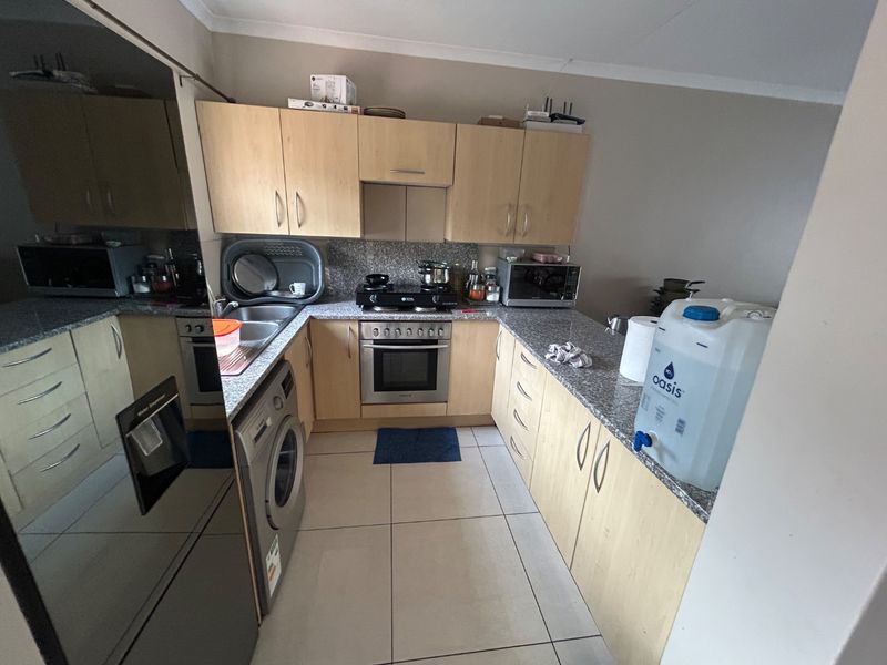 A functional kitchen featuring light wood cabinetry, granite countertops, a built-in oven with gas hob, and tiled flooring.