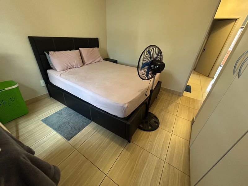 A functional bedroom featuring tiled flooring and a built-in wardrobe, providing a clean and neutral space for rest.