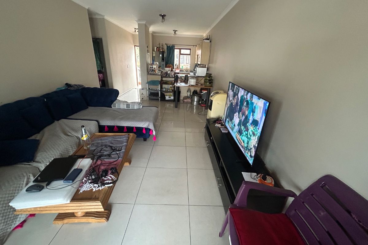 Open-plan living area featuring tiled flooring and a connected kitchen space, providing a functional layout for daily living.