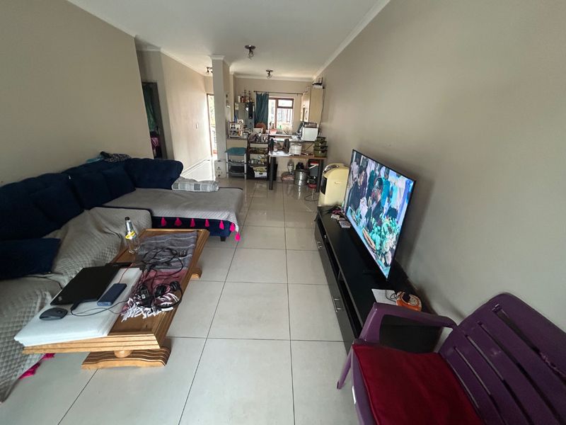 Open-plan living area featuring tiled flooring and a connected kitchen space, providing a functional layout for daily living.