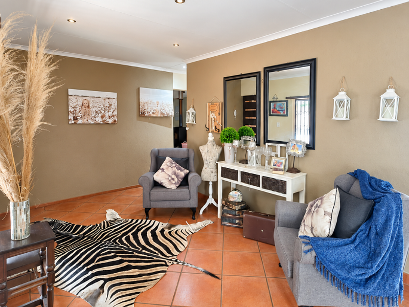 A well-maintained living area featuring terracotta floor tiles, recessed downlighting, and a neutral wall finish, offering a warm and inviting atmosphere.