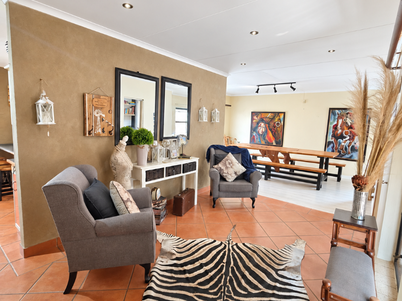 Spacious open-plan living and dining area featuring terracotta floor tiles, recessed downlighting, and a neutral color palette.