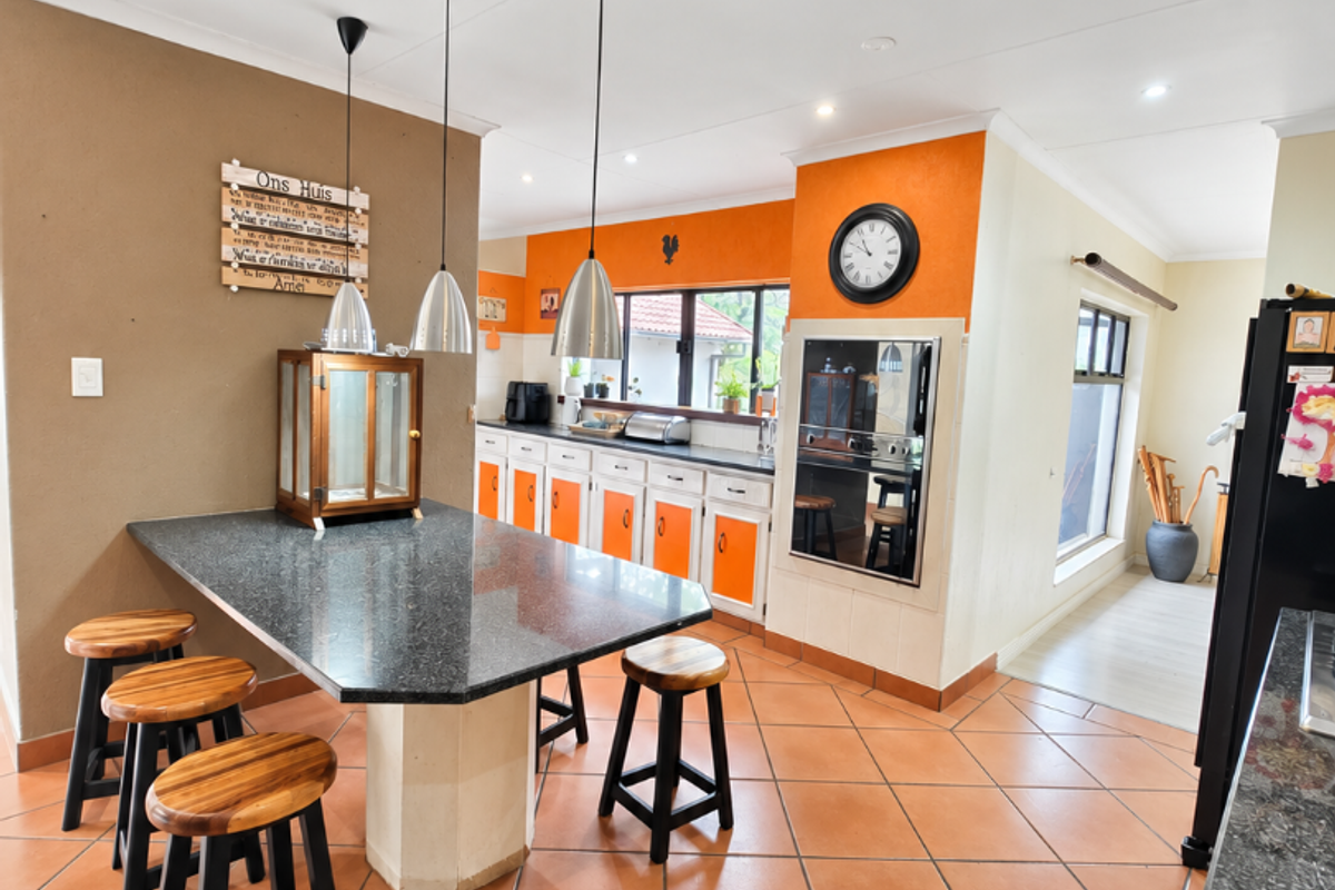 Spacious kitchen featuring granite countertops, built-in oven, ample cabinetry, and tiled flooring, offering a functional layout with integrated dining space.