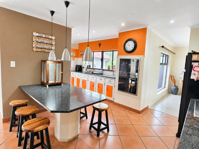 Spacious kitchen featuring granite countertops, built-in oven, ample cabinetry, and tiled flooring, offering a functional layout with integrated dining space.