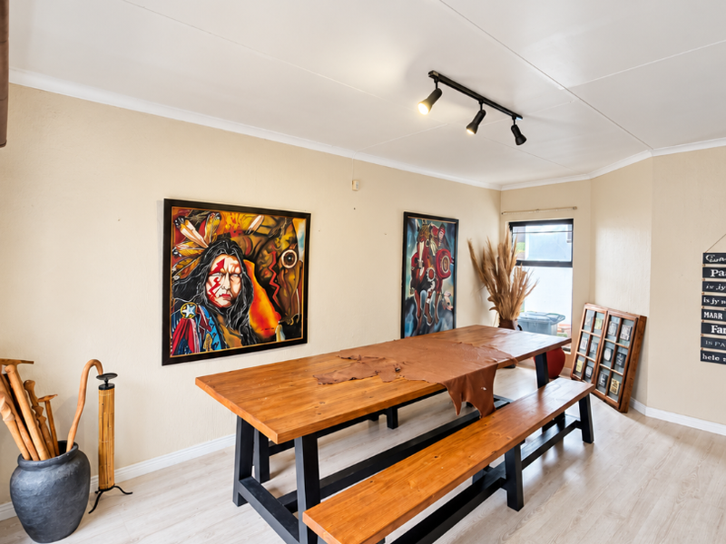 A well-lit dining room featuring modern laminate flooring and adjustable track lighting, providing a clean and functional space for family meals.