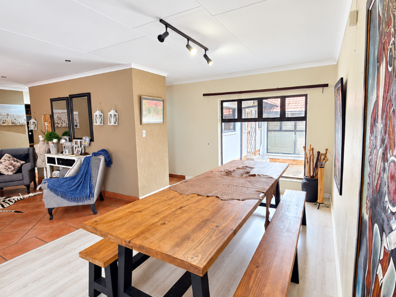 Open plan dining and living area featuring a mix of laminate and terracotta flooring, track lighting, and direct access to an outdoor patio space.
