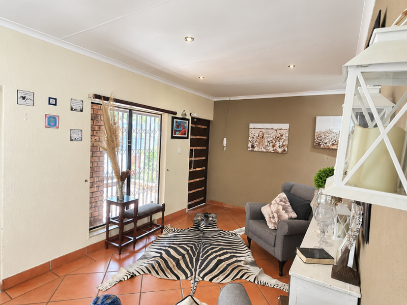 A living room featuring terracotta floor tiles, recessed downlighting, and a sliding glass door with an integrated security gate.