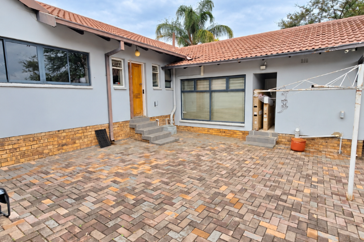 A spacious rear courtyard featuring herringbone paving, terracotta roof tiles, and direct access to the home via multiple entry points.
