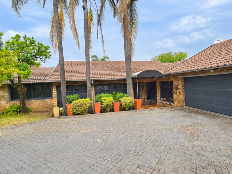 Front exterior view of a facebrick house featuring a large paved driveway, tiled roof, and a double garage.