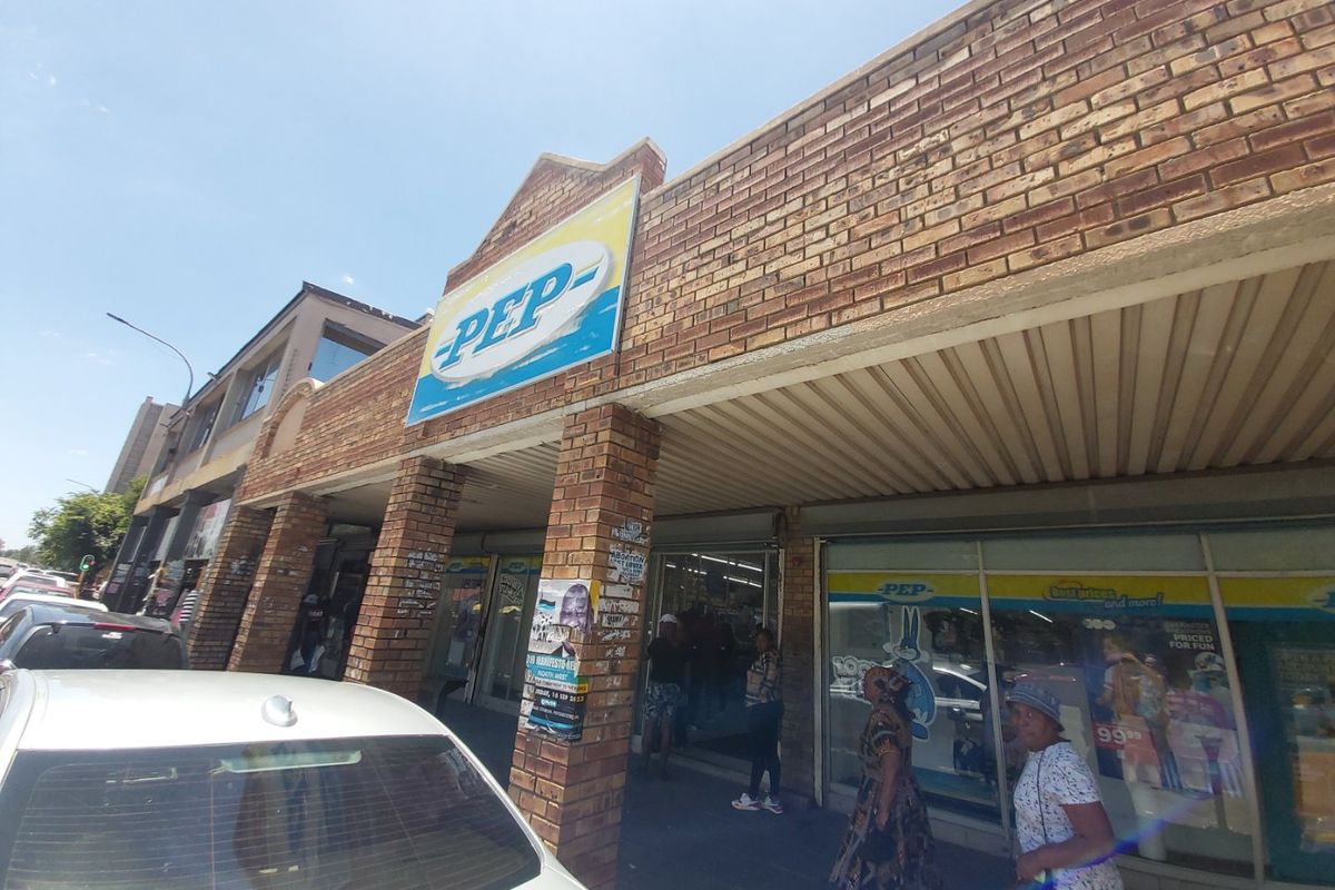 Commercial storefront featuring a brick facade, large display windows, and a covered entrance area, currently occupied by a retail tenant.