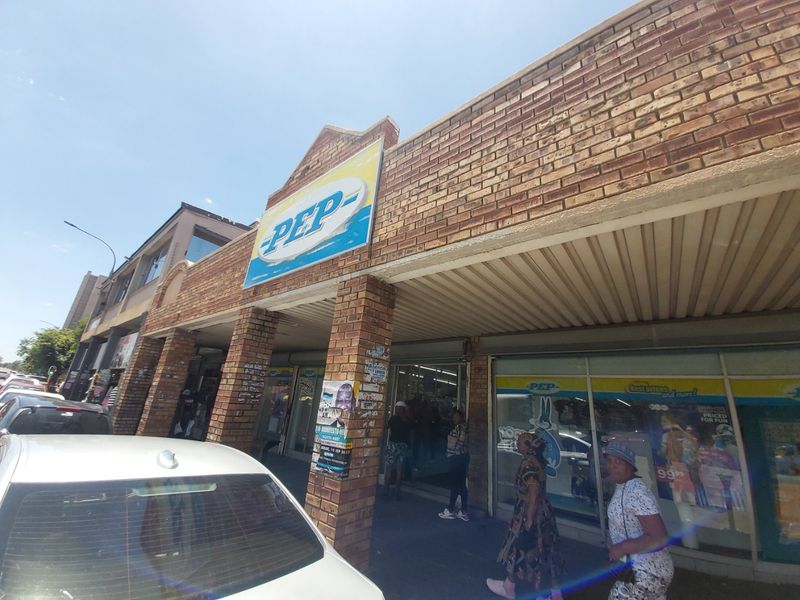 Commercial storefront featuring a brick facade, large display windows, and a covered entrance area, currently occupied by a retail tenant.