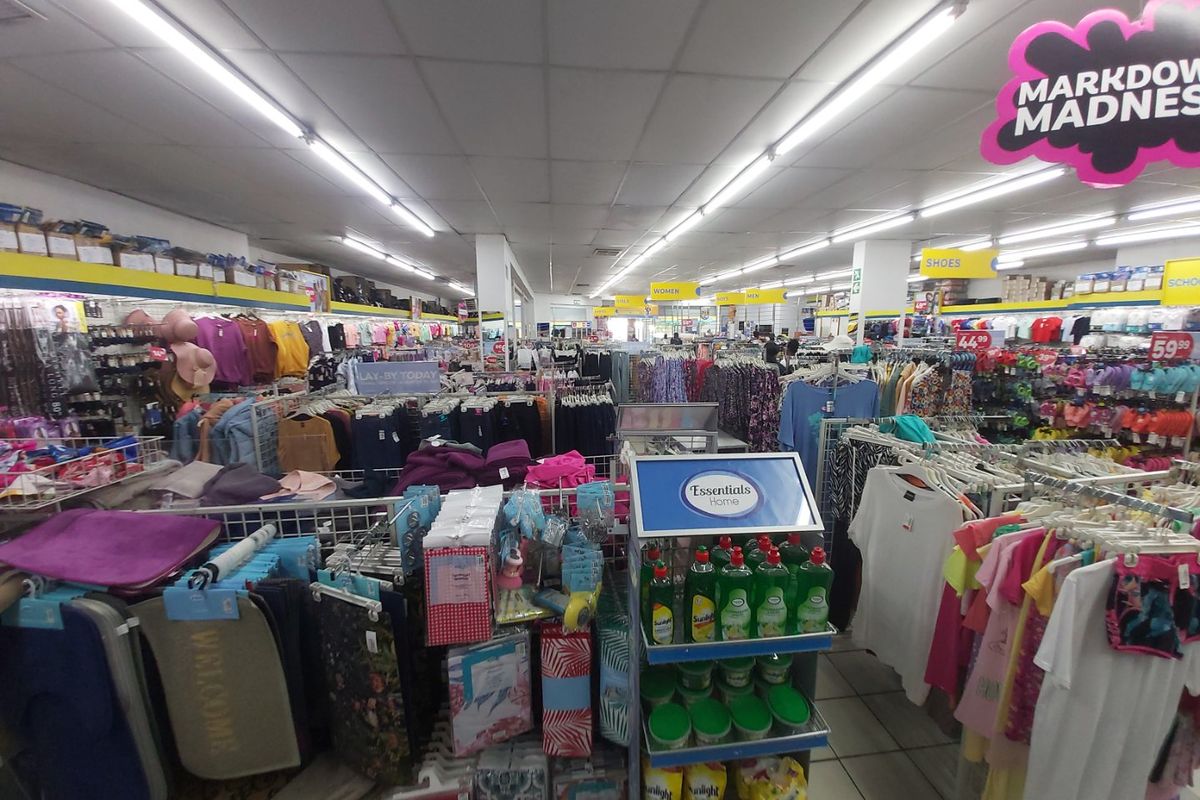 A wide-angle view of a commercial retail store interior featuring suspended ceilings, fluorescent lighting, and tiled flooring throughout the sales floor.