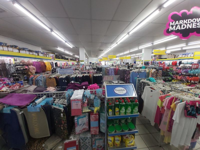 A wide-angle view of a commercial retail store interior featuring suspended ceilings, fluorescent lighting, and tiled flooring throughout the sales floor.