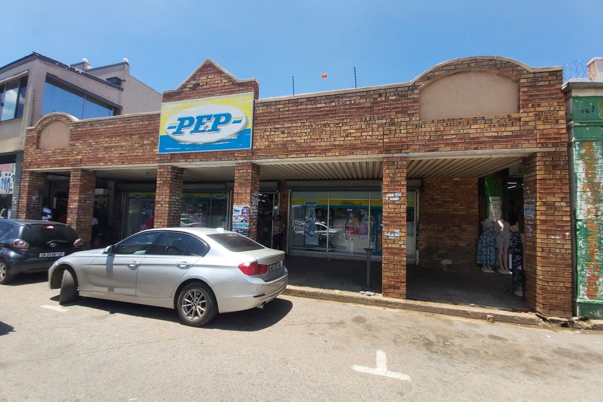Commercial storefront featuring a brick facade with a covered walkway and large glass display windows, situated in a street-level retail location.