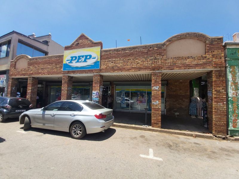 Commercial storefront featuring a brick facade with a covered walkway and large glass display windows, situated in a street-level retail location.