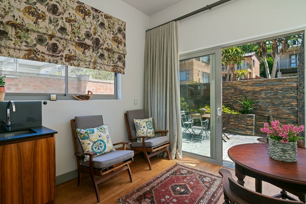 A bright living area featuring laminate flooring, a built-in sink unit, and large sliding glass doors providing seamless access to the outdoor patio.