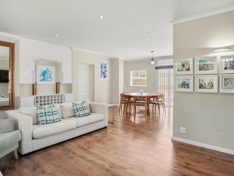 Spacious open-plan living and dining area featuring modern laminate flooring, built-in cabinetry, and recessed lighting, creating a bright and functional living space.