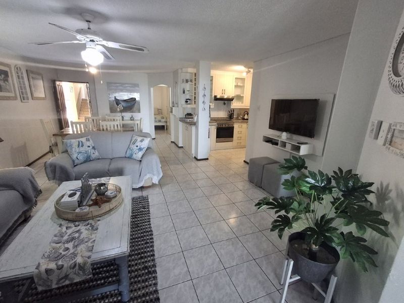 Spacious open-plan living and dining area featuring tiled floors, a ceiling fan, and a functional kitchen with built-in cabinetry and appliances.