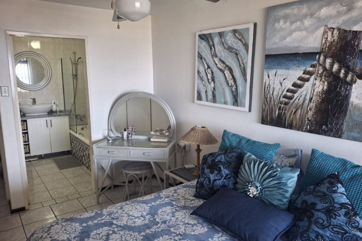 A well-maintained bedroom featuring tiled flooring, a ceiling fan, and an adjoining en-suite bathroom equipped with a vanity, vessel sink, and shower-over-bath combination.
