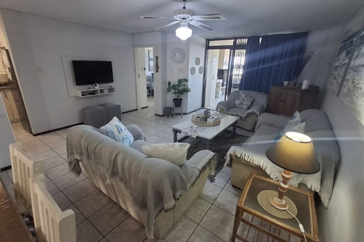 A comfortable living room featuring tiled flooring, a ceiling fan, and direct access to an outdoor patio area through sliding glass doors.