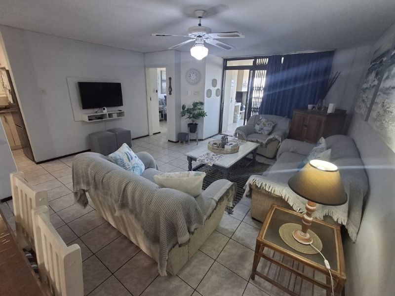 A comfortable living room featuring tiled flooring, a ceiling fan, and direct access to an outdoor patio area through sliding glass doors.