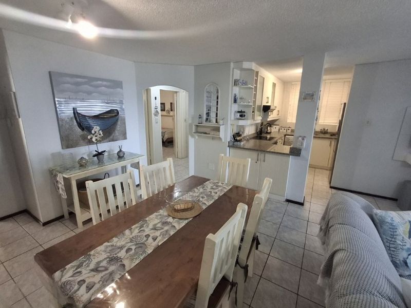 Open-plan dining and kitchen area featuring tiled flooring, built-in cabinetry with granite countertops, and an archway leading to the hallway.