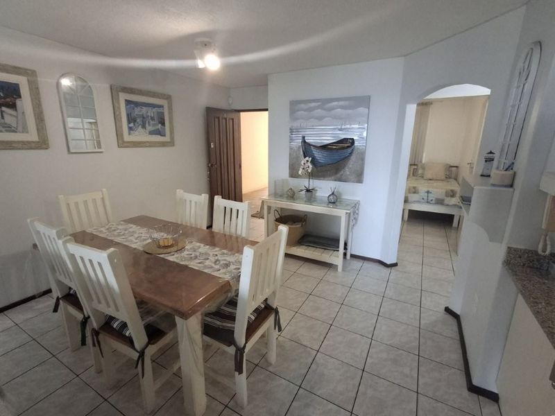 Open plan dining area featuring ceramic floor tiles and an arched entryway leading to the bedroom.