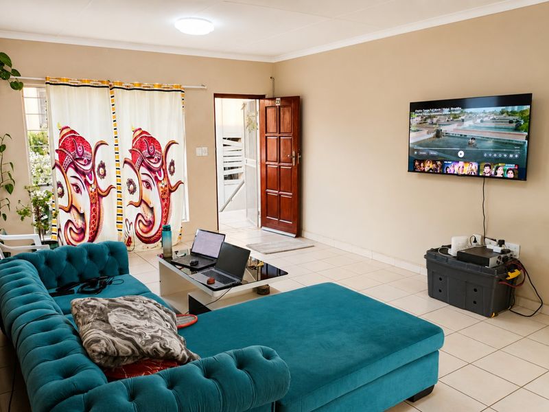 A functional living room featuring tiled flooring, a ceiling light, and a wooden entrance door, providing a neutral base for interior design updates.
