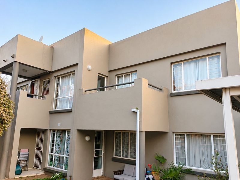 Rear elevation of a multi-story apartment building featuring balconies, aluminium-framed windows, and security gates.