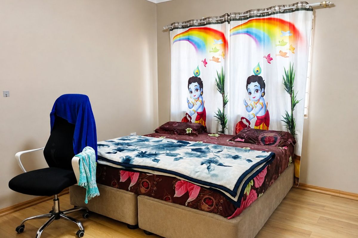 A bedroom featuring laminate flooring and a window with a curtain rod, providing a functional space for rest.