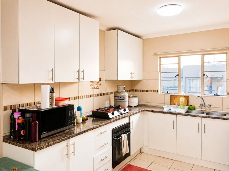 A functional kitchen featuring white cabinetry, laminate countertops, a built-in oven, gas hob, and a double basin sink with tiled backsplash.