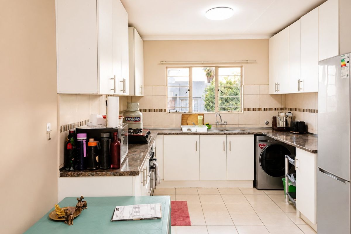 A functional kitchen featuring white cabinetry, laminate countertops, tiled backsplash, and an integrated washing machine, offering a clean and practical workspace.