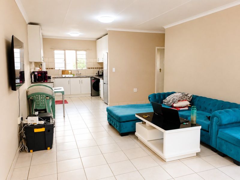 Open-plan living area featuring a functional kitchen with built-in cabinetry and tiled flooring throughout, creating a cohesive and practical living space.