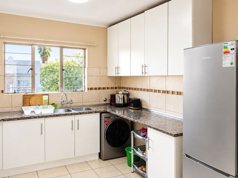 Functional kitchen featuring white cabinetry, laminate countertops, tiled backsplash, and a dedicated space for a washing machine under the counter.