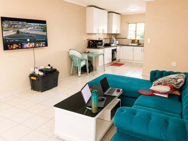 Open-plan living area featuring a functional kitchen with white cabinetry, tiled floors, and a seamless flow into the lounge space.