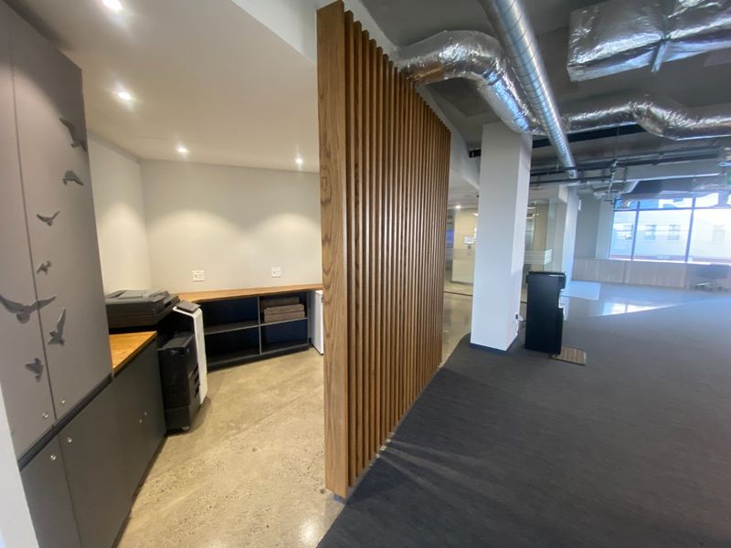 Modern commercial office space featuring polished concrete floors, exposed industrial ductwork, and a decorative timber slat partition wall.