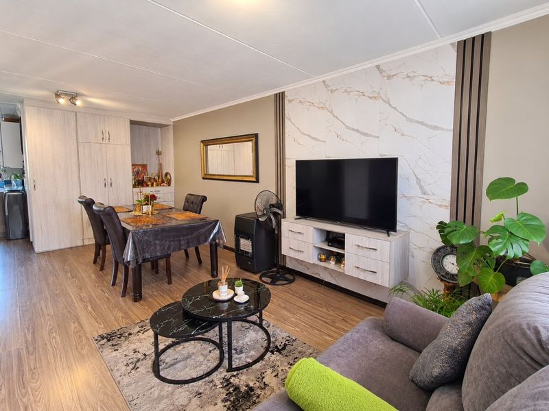 An open-plan living and dining area featuring laminate flooring, a marble-look feature wall with vertical timber accents, and ample built-in storage cabinetry.