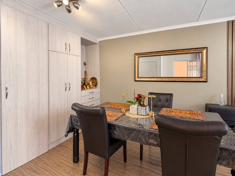 A well-maintained dining area featuring light wood-grain built-in cabinetry, laminate flooring, and neutral wall tones, providing a functional and tidy space.