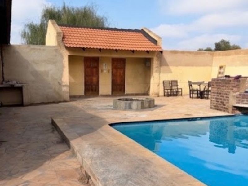 Outdoor pool area featuring a swimming pool, built-in fire pit, and a covered patio structure with tiled roofing.
