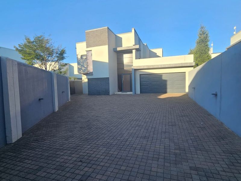 Modern double-story residential property featuring a paved driveway, secure boundary walls, and an integrated double garage.