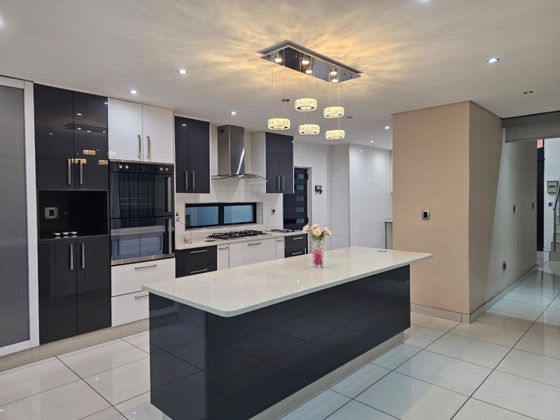 Modern kitchen featuring high-gloss cabinetry, a central island with quartz countertops, built-in appliances, and contemporary recessed lighting.