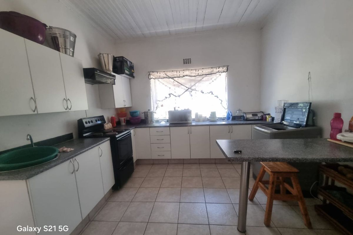 Functional kitchen featuring white cabinetry, laminate countertops, tiled flooring, and a timber ceiling, providing a practical workspace with essential built-in appliances.