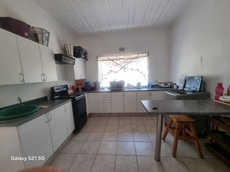Functional kitchen featuring white cabinetry, laminate countertops, tiled flooring, and a timber ceiling, providing a practical workspace with essential built-in appliances.